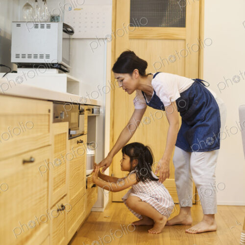 Family home. A woman and a girl bending down to look in an oven. Family home. A woman and a girl bending down to look in an oven.