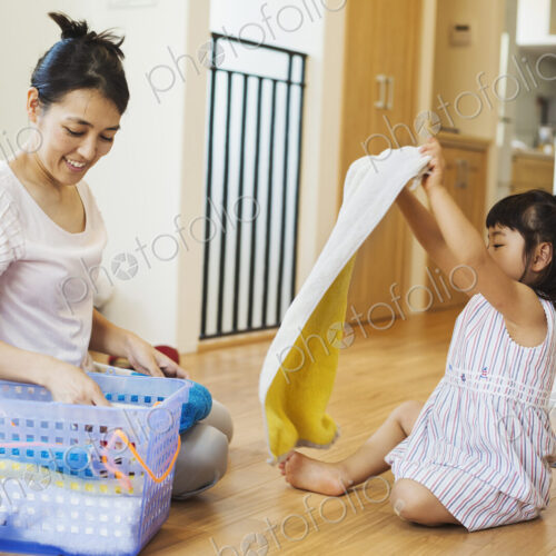 Family home. A woman and her daughter folding clean laundry.