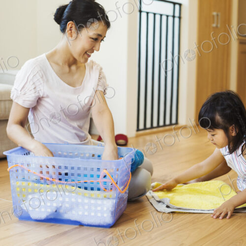 Family home. A woman and her daughter folding clean laundry.