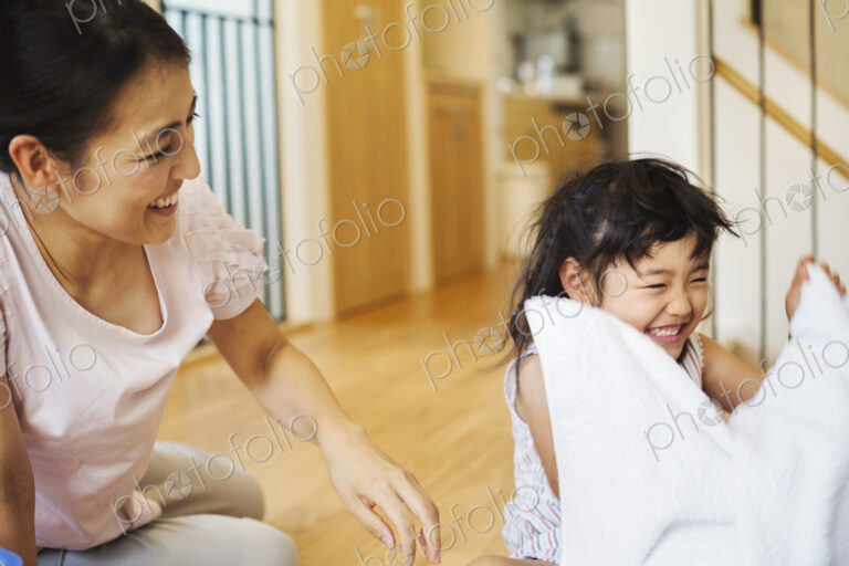 Family home. A woman and her daughter folding clean laundry.