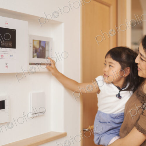 Family home. A woman and her daughter looking at a screen on the wall, controls of an… Family home. A woman and her daughter looking at a screen on the wall, controls of an…