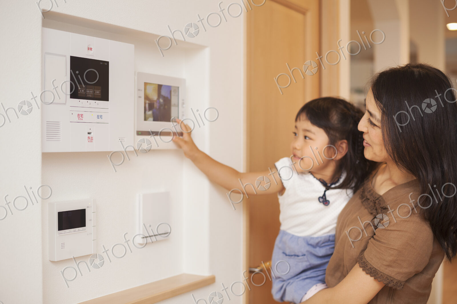 Family home. A woman and her daughter looking at a screen on the wall, controls of an…