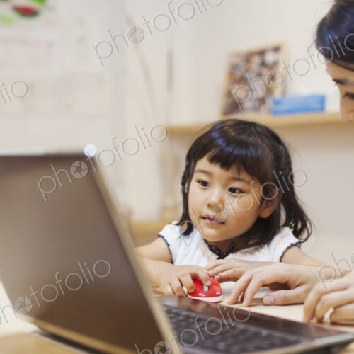 Family home. A woman and her daughter seated at a table looking at the screen of a laptop. Family home. A woman and her daughter seated at a table looking at the screen of a laptop.
