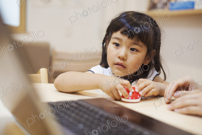 Family home. A woman and her daughter seated at a table looking at the screen of a laptop.