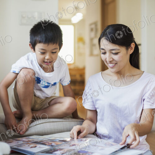 Family home. A woman and her son looking at a photographic album. Family home. A woman and her son looking at a photographic album.