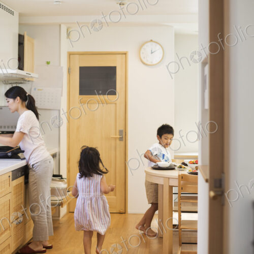 Family home. A woman and two children, a girl and a boy laying the table for a meal. Family home. A woman and two children, a girl and a boy laying the table for a meal.