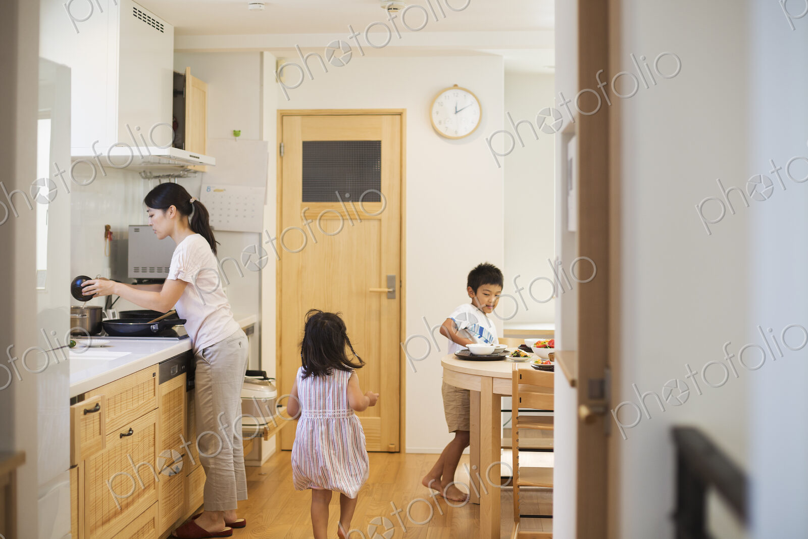 Family home. A woman and two children, a girl and a boy laying the table for a meal.