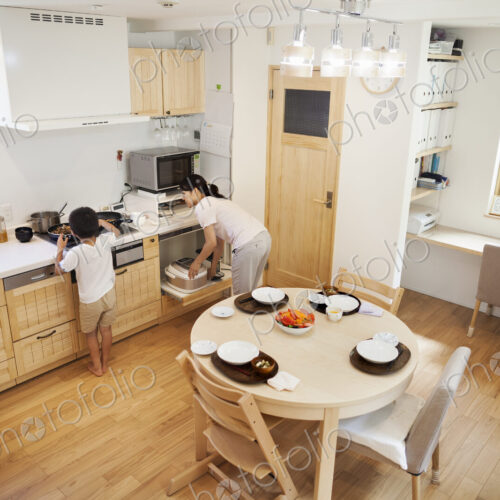 Family home. A woman bending to reach dishes in a kitchen cupboard. Family home. A woman bending to reach dishes in a kitchen cupboard.