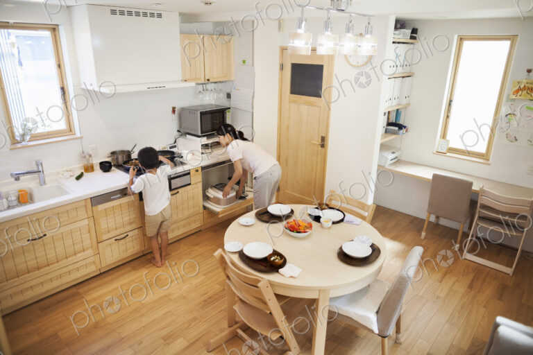 Family home. A woman bending to reach dishes in a kitchen cupboard.