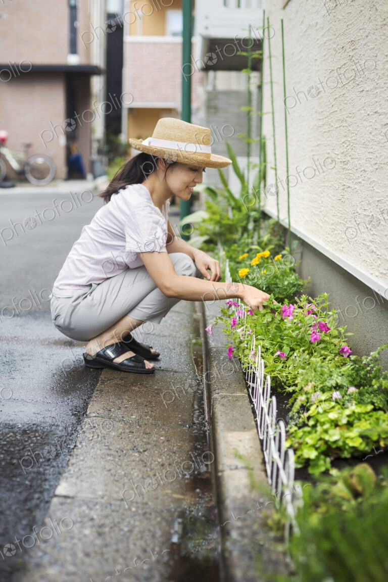 Family home. A woman crouching and planting flowers in a small strip of soil.