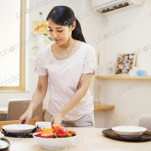 Family home. A woman preparing a meal arranging dishes on a table. Family home. A woman preparing a meal arranging dishes on a table.