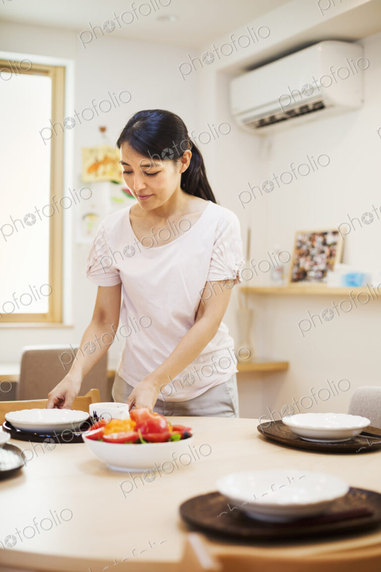 Family home. A woman preparing a meal arranging dishes on a table.
