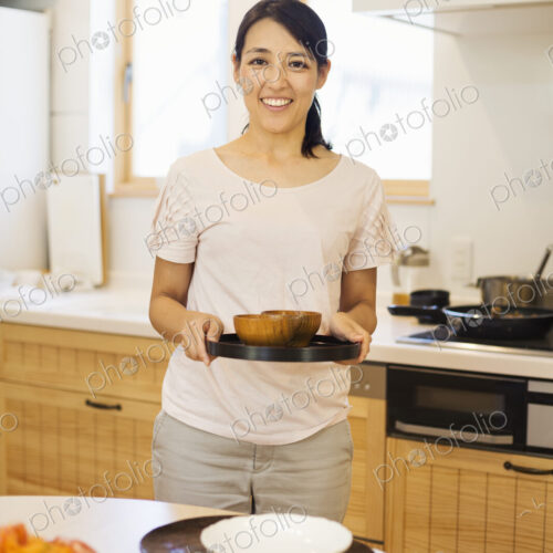 Family home. A woman preparing a meal arranging dishes on a table. Family home. A woman preparing a meal arranging dishes on a table.
