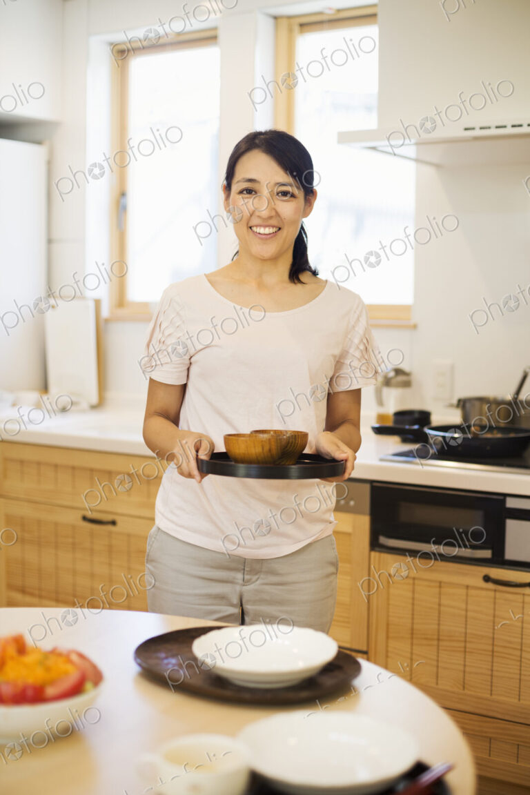 Family home. A woman preparing a meal arranging dishes on a table.