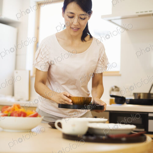 Family home. A woman preparing a meal arranging dishes on a table. Family home. A woman preparing a meal arranging dishes on a table.