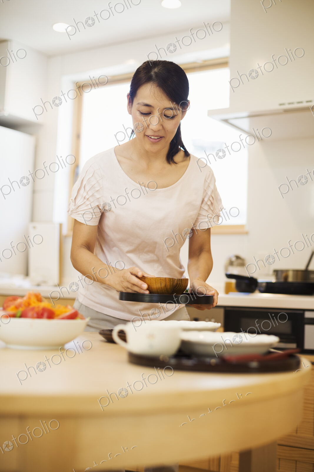 Family home. A woman preparing a meal arranging dishes on a table.