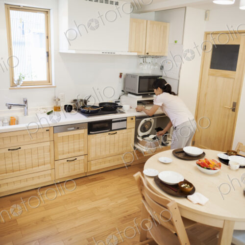 Family home. A woman preparing a meal in a kitchen. Family home. A woman preparing a meal in a kitchen.