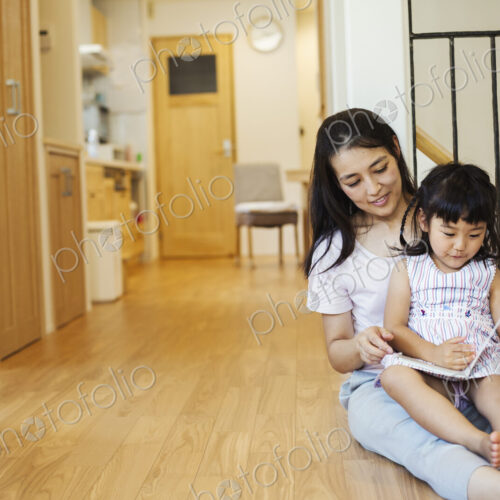 Family home. A woman seated with her daughter on her lap, looking at a book. Family home. A woman seated with her daughter on her lap, looking at a book.