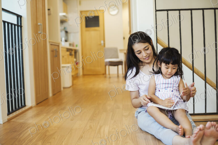 Family home. A woman seated with her daughter on her lap, looking at a book.