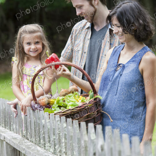 Family standing in a garden with a basket of vegetables. Family standing in a garden with a basket of vegetables.