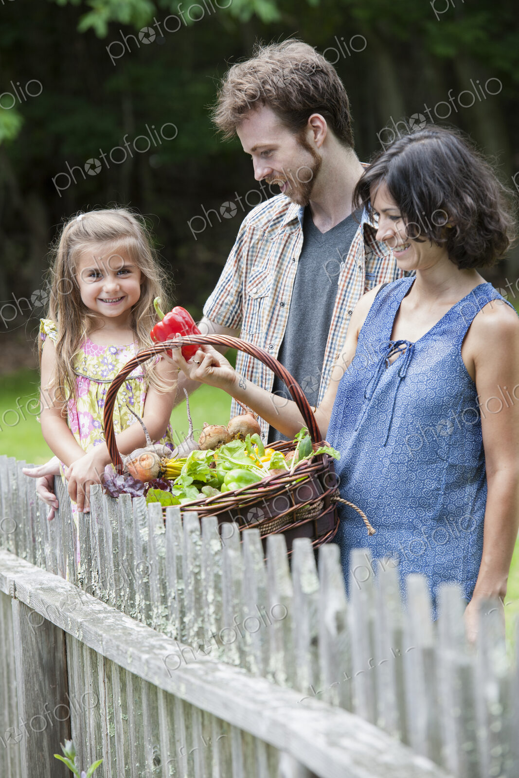 Family standing in a garden with a basket of vegetables.