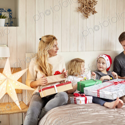 Family, two adults and two children on Christmas morning opening presents Family, two adults and two children on Christmas morning opening presents