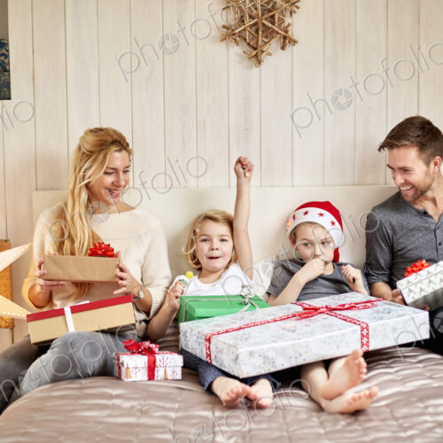 Family, two adults and two children on Christmas morning opening presents Family, two adults and two children on Christmas morning opening presents