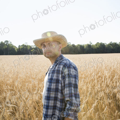Farmer in a checked shirt and hat in a cornfield Farmer in a checked shirt and hat in a cornfield