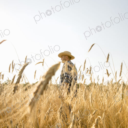 Farmer in jeans and straw hat standing in a cornfield