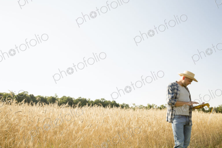 Farmer in jeans and straw hat, using a digital tablet