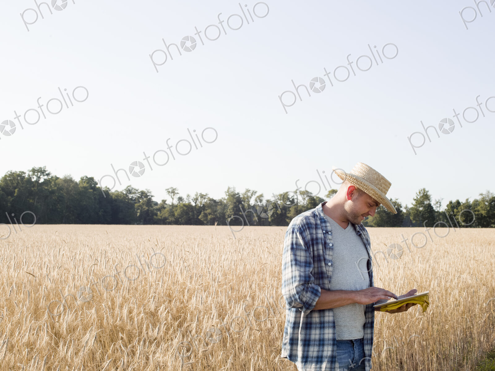Farmer in jeans and straw hat, using a digital tablet