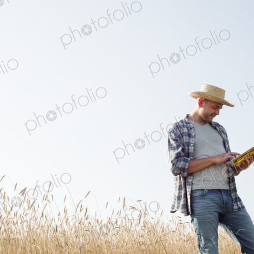 Farmer in jeans and straw hat, using a digital tablet Farmer in jeans and straw hat, using a digital tablet