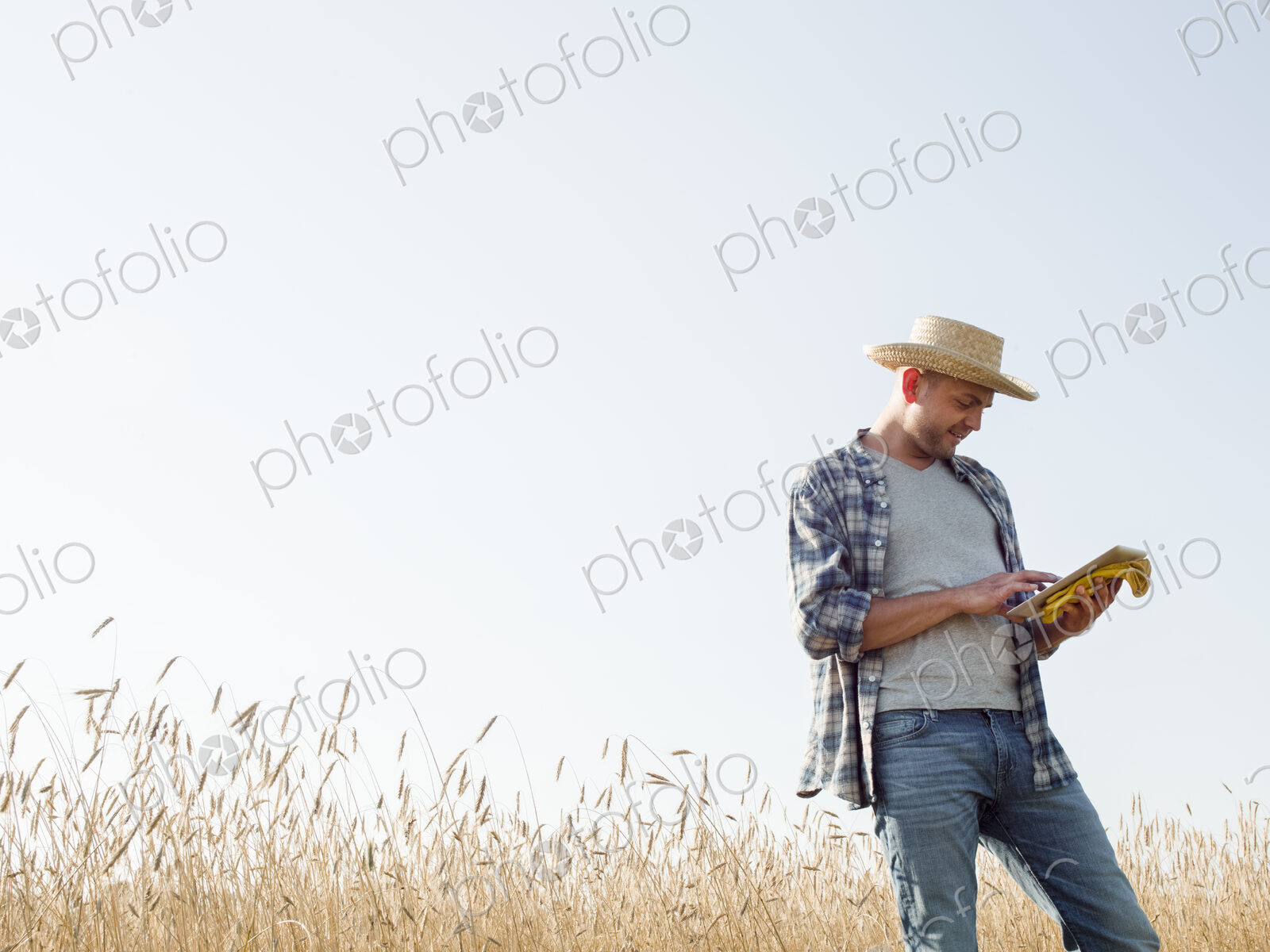Farmer in jeans and straw hat, using a digital tablet