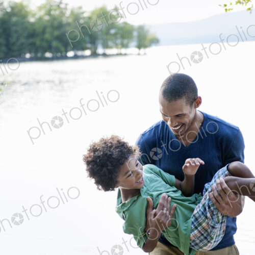 Father playing with his son carrying him in his arms. Father playing with his son carrying him in his arms.