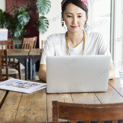 Female Japanese professional sitting at a table in a co-working space, using laptop…