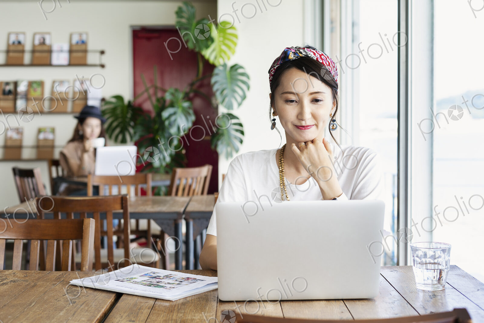 Female Japanese professional sitting at a table in a co-working space, using laptop…