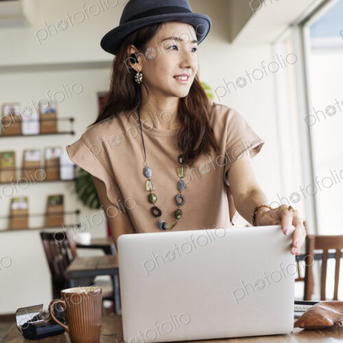 Female Japanese professional sitting at a table in a co-working space, using laptop…