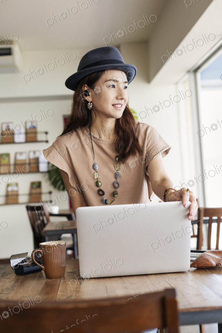 Female Japanese professional sitting at a table in a co-working space, using laptop…