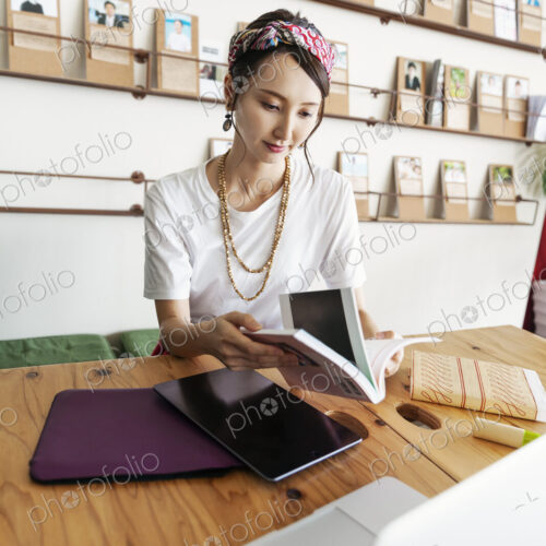 Female Japanese professional sitting at table in a co-working space, using digital…