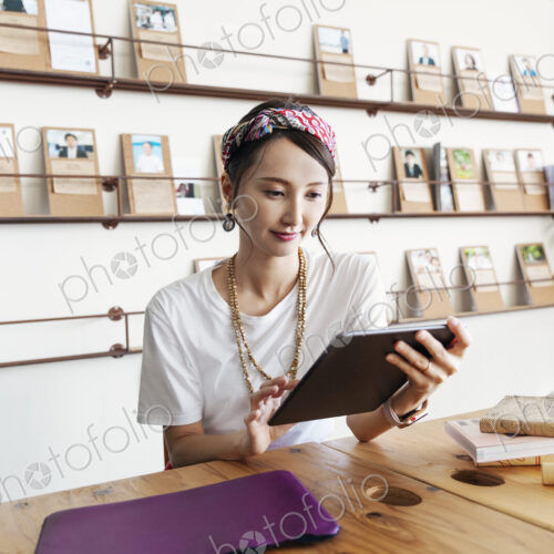 Female Japanese professional sitting at table in a co-working space, using digital…
