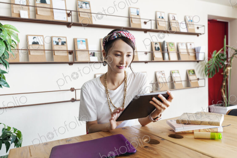 Female Japanese professional sitting at table in a co-working space, using digital…