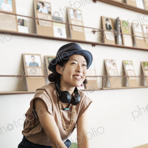 Female Japanese professional wearing Trilby hat and headphones sitting in a co-working… Female Japanese professional wearing Trilby hat and headphones sitting in a co-working…