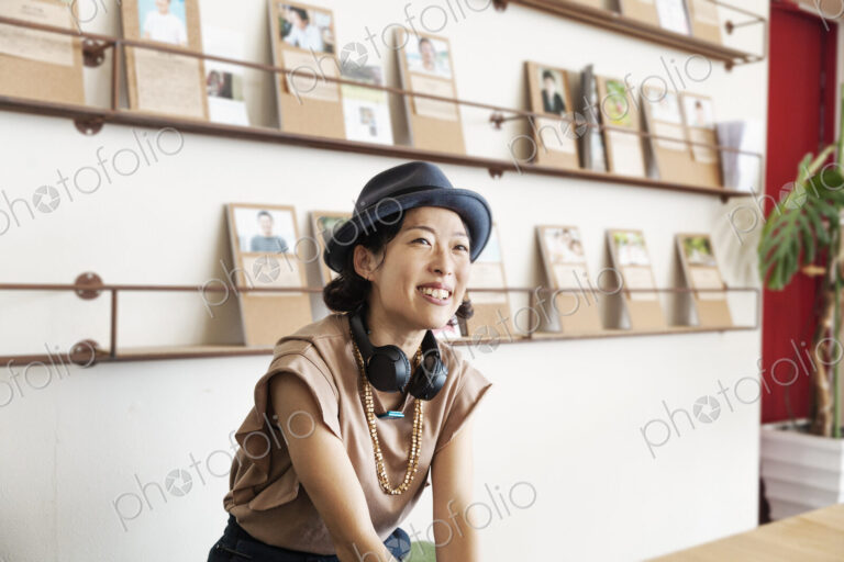 Female Japanese professional wearing Trilby hat and headphones sitting in a co-working…