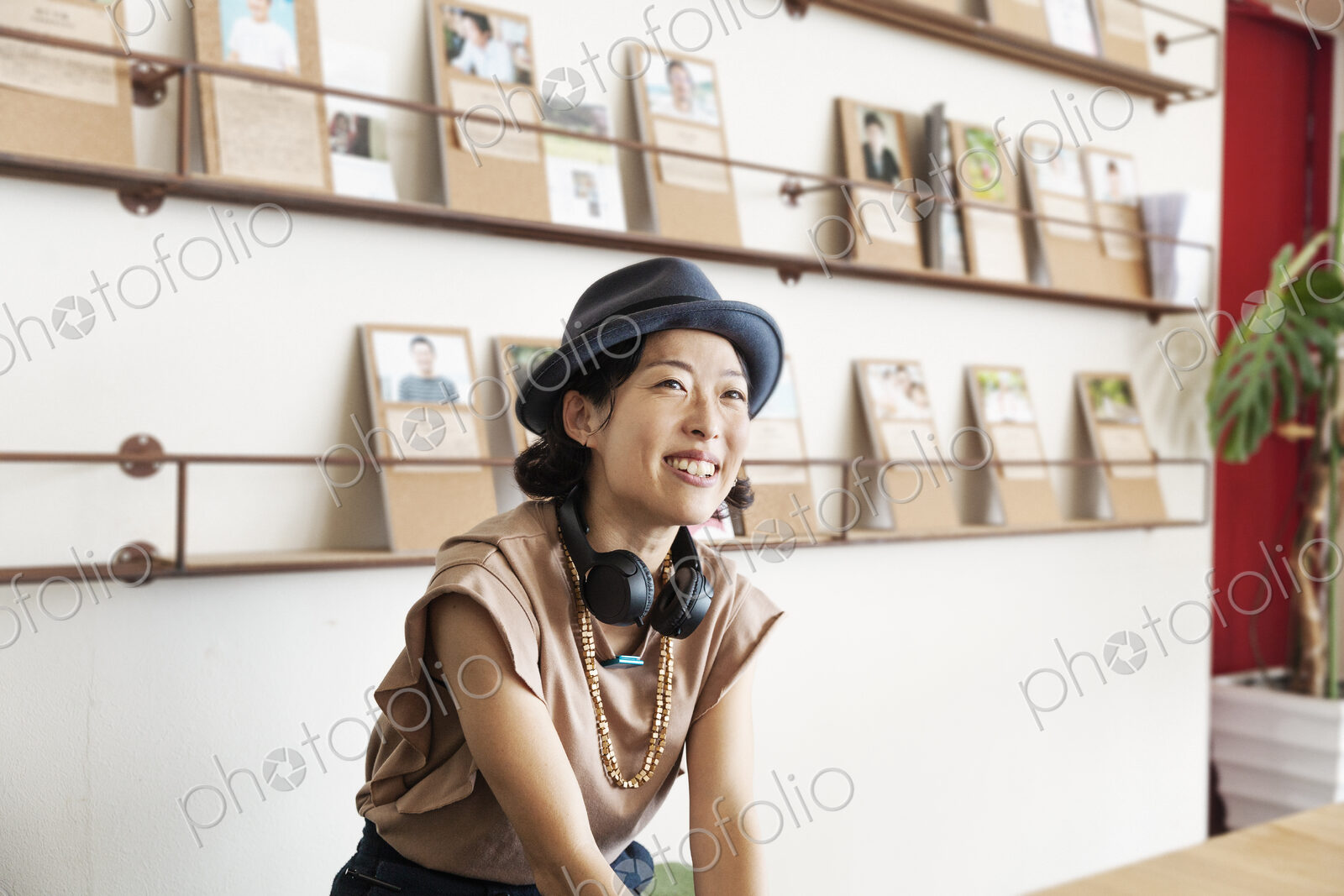 Female Japanese professional wearing Trilby hat and headphones sitting in a co-working…