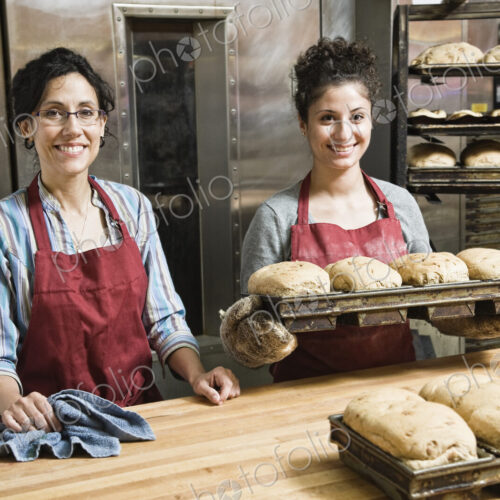 Female bakers working at a bakery with loaves of bread.