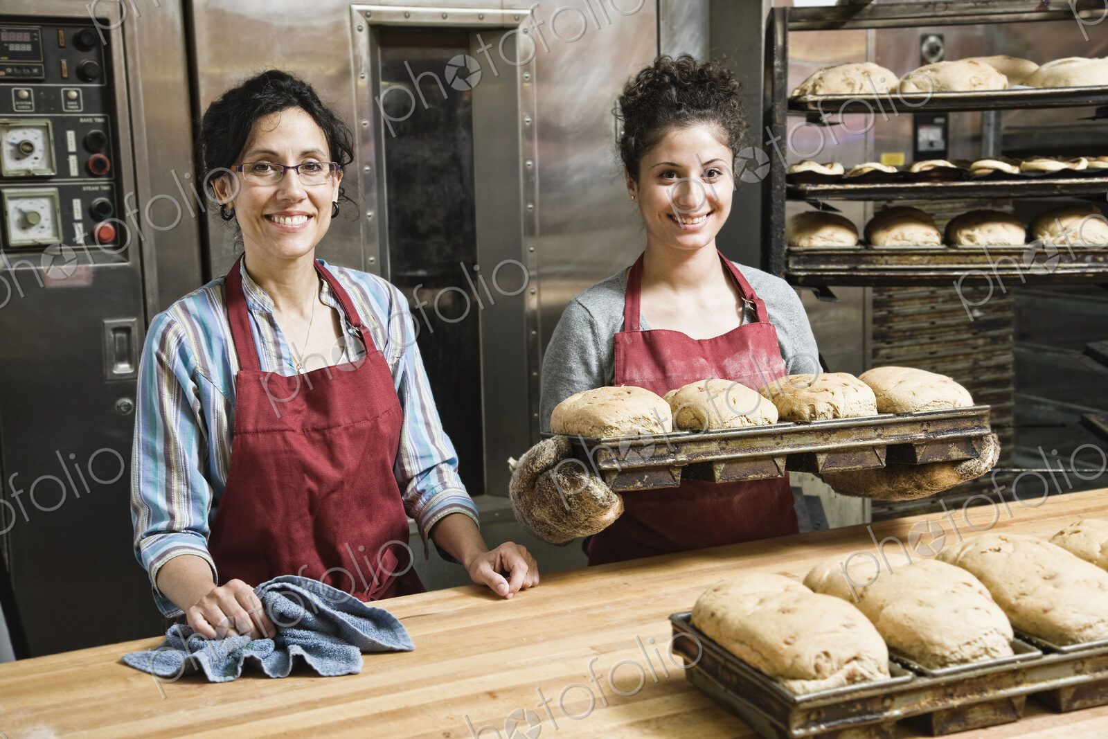 Female bakers working at a bakery with loaves of bread.