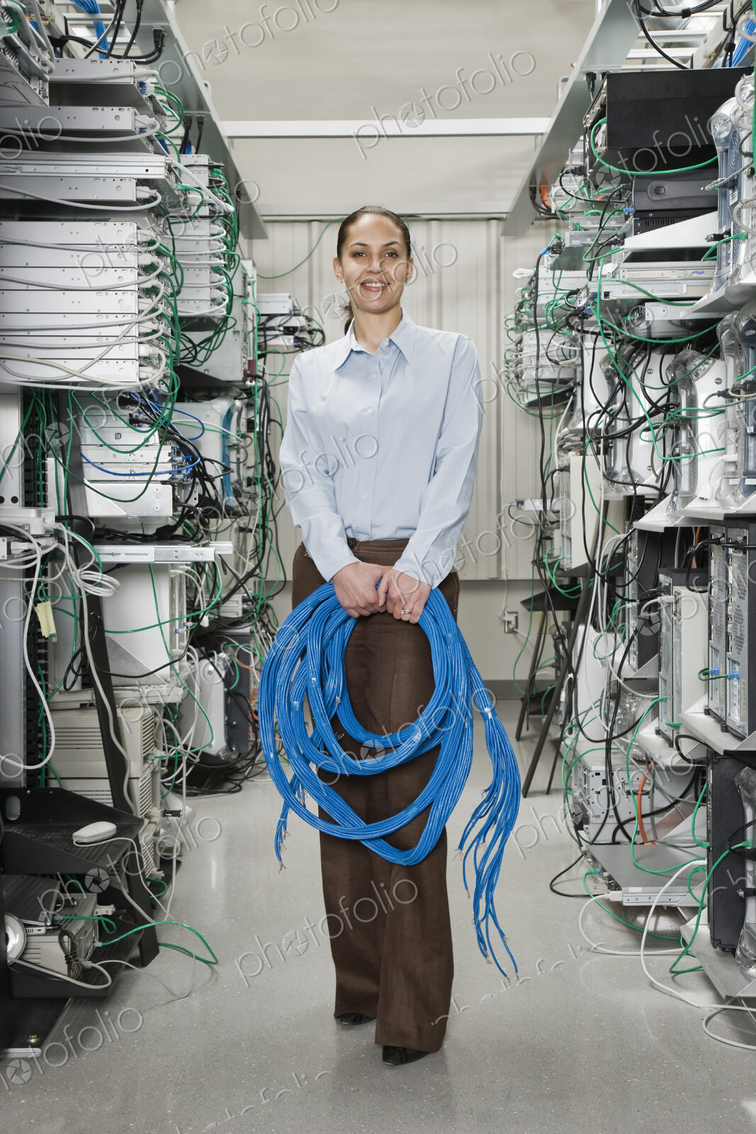 Female computer technician holding CAT 5 cables and standing in the aisle of a…
