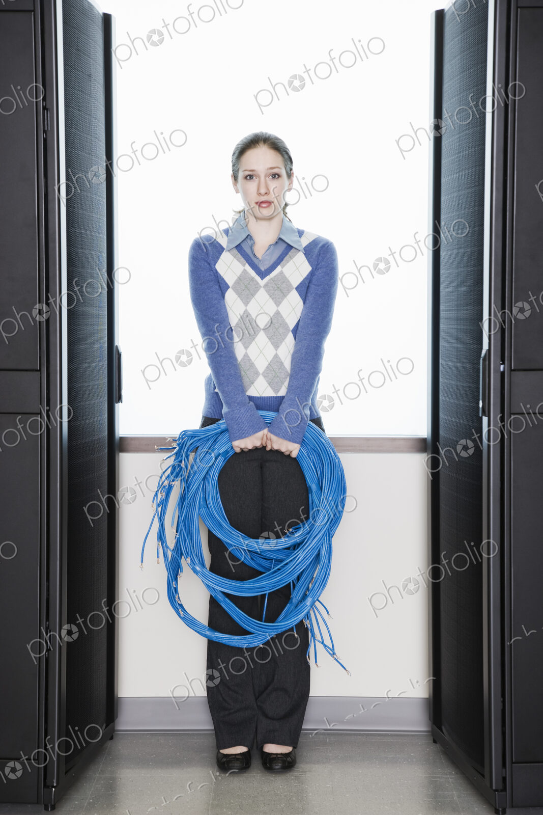 Female computer technician holding CAT 5 cables and standing in the aisle of a…