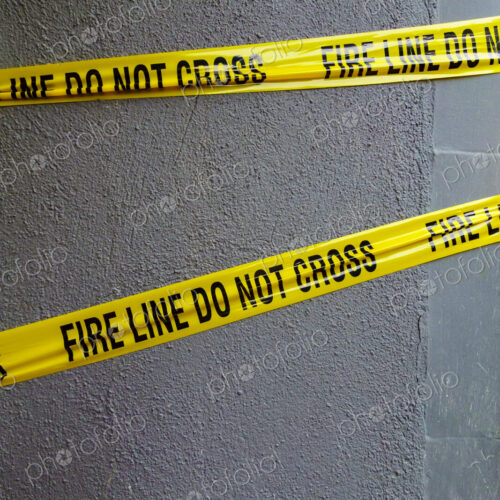 Fire Line Do Not Cross tape, yellow tape with black lettering stretched across a wall.