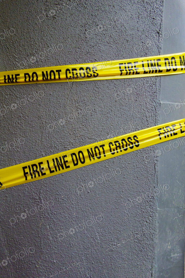 Fire Line Do Not Cross tape, yellow tape with black lettering stretched across a wall.